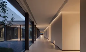 A modern corridor with glass walls and ceiling-to-floor windows.