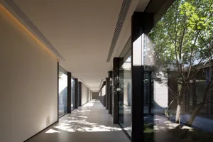 Modern interior corridor with glass walls and sunlight streaming through, highlighting minimalist design principles.