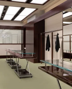 Modern clothing shop with glass tables and metal railings.