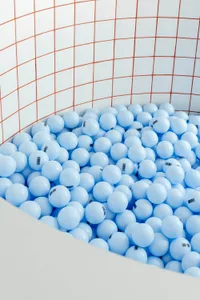 A minimalist playroom filled with blue plastic balls on a white tiled floor.