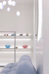 A minimalistic retail space featuring white walls, white shelves, and a white couch.