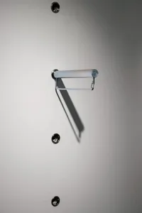 A minimalist metal towel rack mounted on a plain white wall.