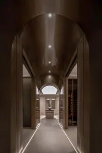 A modern interior featuring a glass and steel corridor with arched ceilings and illuminated pathways.