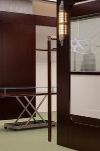 A minimalist interior design featuring a modern metal shelf with a glass top on a green carpeted floor.