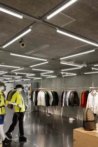 現代服裝店展示區，搭配工業風混凝土牆面與光纖照明。