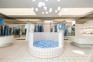 A modern retail interior featuring a ball pit and hanging cloud-shaped lights.