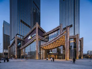 A modern shopping center entrance featuring glass facade, stone accents, and metallic elements.