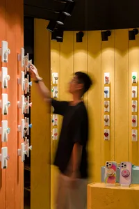 A customer interacts with a display of colorful phone grip accessories in a retail store.