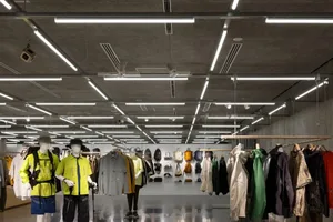 Industrial design retail shop featuring concrete kiosk with clothing items on display.