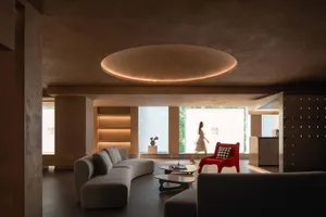 A modern interior design featuring a living room with concrete walls and a red accent chair.