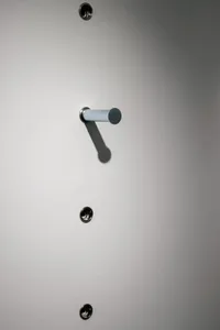A metal lock with a gray cylinder handle attached to a smooth, white surface.