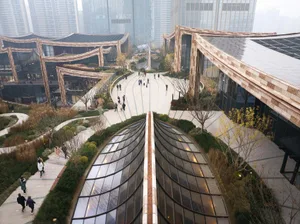 People walking in a modern public space featuring glass and concrete architectural elements.