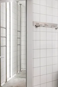 A modern public space with white tiled walls and arms attached horizontally with writing
