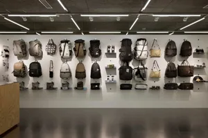 Various backpacks and bags displayed on a wall within an interior space.