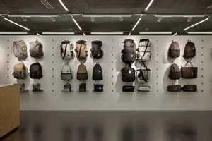 A row of backpacks and bags hanging on a pegboard in a retail storefront.
