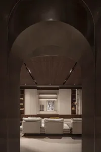 A modern living room featuring wood-paneled walls, upholstered furniture, and minimalist decor.
