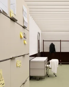 Modern minimalist office space featuring metal cabinets and plastic drawers, with a green carpet and white walls.