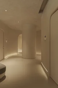 A minimalist interior space featuring concrete walls and floors, highlighted by recessed lighting and minimalist decor.