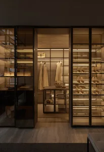 Modern closet with glass shelves, hanging clothing, and shoe storage