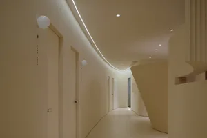 A modern hospital hallway with neutral-colored walls, a smooth floor, and curved architectural elements.