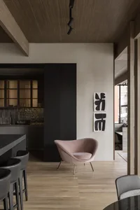 Modern living room featuring minimalist decor with wooden furniture and a pink armchair.