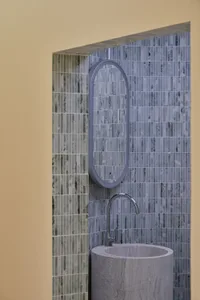 Modern minimalist bathroom featuring marble tiles and a cylindrical sink.
