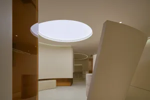 A minimalist interior with white walls and concrete flooring, featuring a circular light fixture.