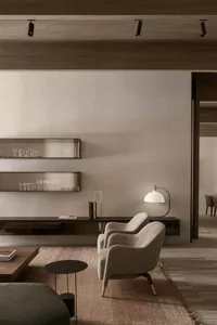 Interior of a modern minimalist living room featuring a wooden frame, grey upholstered armchair, and a natural-fiber rug.