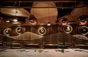 Modern restaurant dining area featuring a combination of copper, glass, and wood materials.