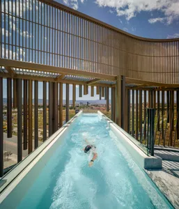 Swimmer in a modern rooftop swimming pool enclosed by glass walls.