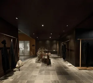 一間現代都會服飾店，採用石材地板與混凝土牆面，呈現極簡設計與工業風照明。