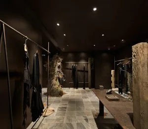 A retail store with dark interior walls and wood-texture decor, featuring clothing racks.