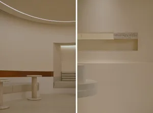A modern interior design featuring neutral materials and a curved ceiling with hidden lighting.