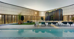 Modern outdoor dining area featuring wood and greenery with a swimming pool.