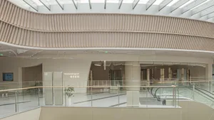An interior view of a modern shopping center extension showcasing glass, concrete, and wooden architectural elements.
