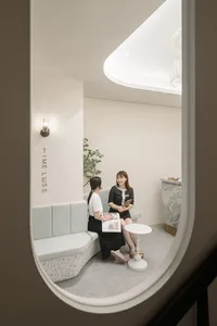 Two women in a modern spa reception area with a sleek, minimalist interior.