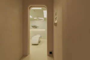 A minimalist hospital room with white furniture and a white ceiling.