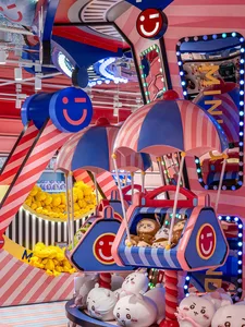 A brightly colored and whimsical game room arcade with plastic umbrellas filled with stuffed animals.