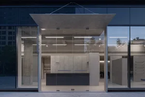 A minimalist storefront with large glass windows and concrete elements.