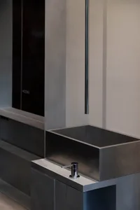 Minimalist interior design featuring a sleek, modern metal basin, with a chrome faucet and black cabinets.
