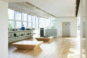 A minimalist retail display room featuring a concrete floor and walls, with various products and accessories arranged on shel