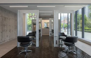 Modern concrete and glass interior of a salon with sleek design elements and bright lighting.