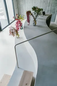 A minimalistic lobby with concrete walls and a curved, white staircase