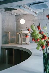 A modern restaurant interior with concrete walls and wooden furniture.