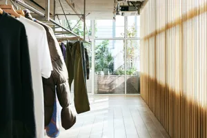 Modern retail store interior with wooden walls and clothing racks.