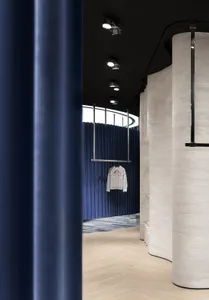 A minimalist clothing store interior with concrete and blue pleated fabric walls.