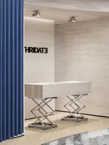 A modern office entry featuring a minimalist concrete desk with metallic legs and a blue curtain