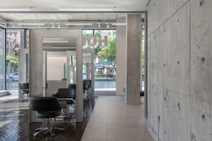 Modern salon interior with black chairs, concrete walls, and glass elements.