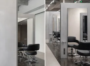 Modern salon interior featuring metal and glass fixtures with concrete flooring.