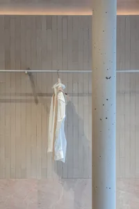 Clothing hanger with white fabric hanging on a wall-mounted horizontal bar in a concrete interior space.